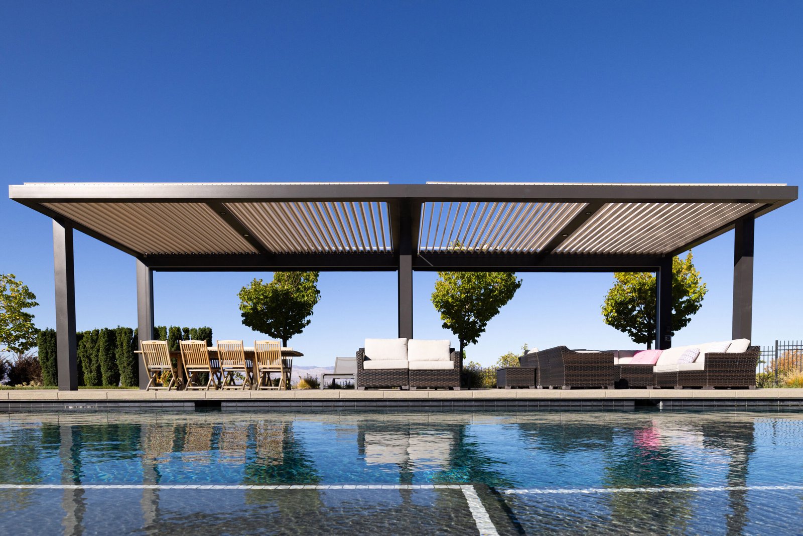 Modern louvered cabana providing shade for poolside dining and seating